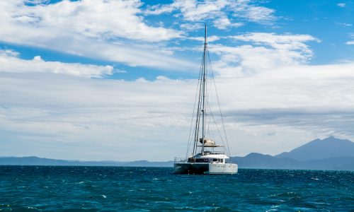 mesmerizing scenery of a yacht on the blue sea with white clouds in the background